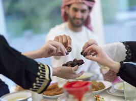 moderno multiétnico musulmán familia compartiendo un cuenco de fechas mientras disfrutando iftar cena juntos durante un Ramadán banquete a hogar foto