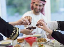 moderno multiétnico musulmán familia compartiendo un cuenco de fechas mientras disfrutando iftar cena juntos durante un Ramadán banquete a hogar foto