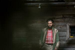 portrait of young hipster in front of wooden house photo