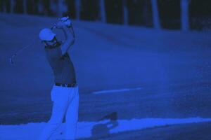 golfer hitting a sand bunker shot photo