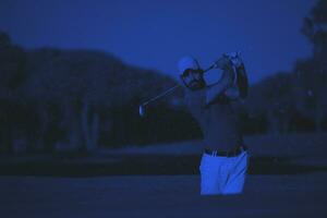 golfista profesional golpeando un tiro de búnker de arena foto