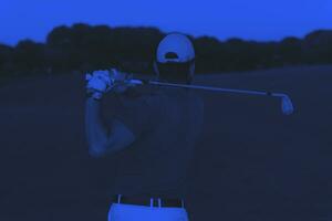 golfer hitting a sand bunker shot on sunset photo