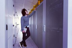 IT engineer working on a tablet computer in server room photo