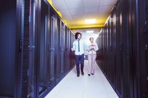 engineer showing working data center server room to female chief photo