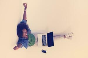 african american woman sitting on floor with laptop top view photo