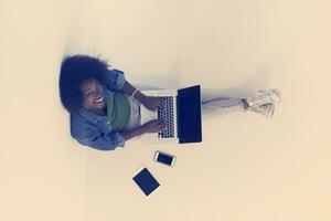 african american woman sitting on floor with laptop top view photo