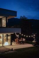 A group of young diverse people having dinner on the terrace of a modern house in the evening. Fun for friends and family. Celebration of holidays, weddings with barbecue. photo