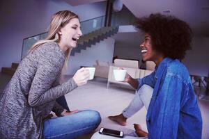 young multiethnic women sit on the floor and drinking coffee photo