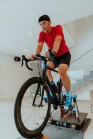 A man riding a triathlon bike on a machine simulation in a modern living room. Training during pandemic conditions. photo