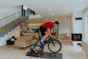 A man riding a triathlon bike on a machine simulation in a modern living room. Training during pandemic conditions. photo