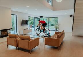 A man riding a triathlon bike on a machine simulation in a modern living room. Training during pandemic conditions. photo