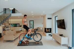 un hombre montando un triatlón bicicleta en un máquina simulación en un moderno vivo habitación. formación durante pandemia condiciones. foto