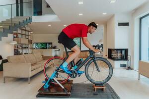 A man riding a triathlon bike on a machine simulation in a modern living room. Training during pandemic conditions. photo