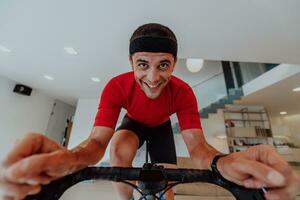 A man riding a triathlon bike on a machine simulation in a modern living room. Training during pandemic conditions. photo