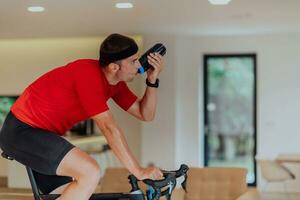 A man riding a triathlon bike on a machine simulation in a modern living room. Training during pandemic conditions. photo