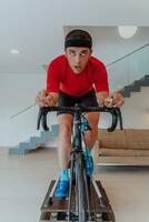 A man riding a triathlon bike on a machine simulation in a modern living room. Training during pandemic conditions. photo