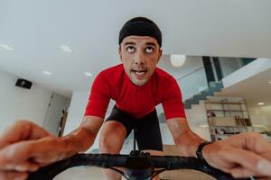 A man riding a triathlon bike on a machine simulation in a modern living room. Training during pandemic conditions. photo