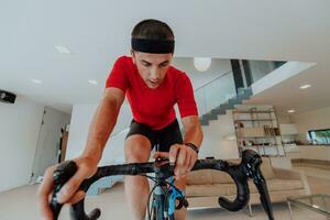 A man riding a triathlon bike on a machine simulation in a modern living room. Training during pandemic conditions. photo