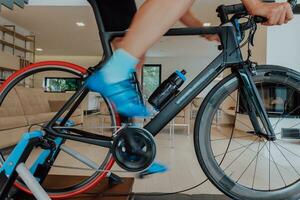 A man riding a triathlon bike on a machine simulation in a modern living room. Training during pandemic conditions. photo