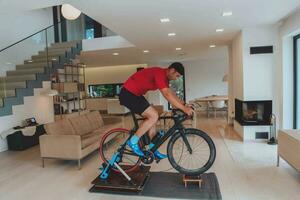 A man riding a triathlon bike on a machine simulation in a modern living room. Training during pandemic conditions. photo