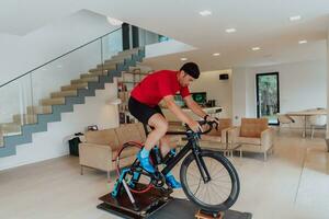 un hombre montando un triatlón bicicleta en un máquina simulación en un moderno vivo habitación. formación durante pandemia condiciones. foto