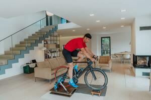 A man riding a triathlon bike on a machine simulation in a modern living room. Training during pandemic conditions. photo