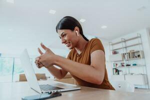 Woman sitting in living room using laptop look at cam talk by video call with business friend relatives, head shot. Job interview answering questions. photo