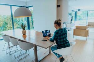 Woman sitting in living room using laptop look at cam talk by video call with business friend relatives, head shot. Job interview answering questions. photo