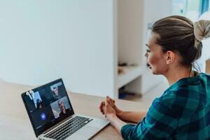 Woman sitting in living room using laptop look at cam talk by video call with business friend relatives, head shot. Job interview answering questions. photo