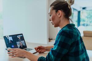 Woman sitting in living room using laptop look at cam talk by video call with business friend relatives, head shot. Job interview answering questions. photo