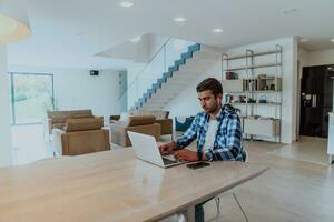 el hombre sentado a un mesa en un moderno vivo habitación, con auriculares utilizando un ordenador portátil para negocio vídeo charlar, conversacion con amigos y entretenimiento foto