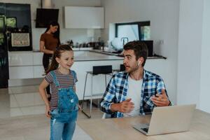 Father and daughter in modern house talking together on laptop with their family during holidays. The life of a modern family photo