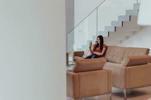 Woman using smartphone for video call while sitting in modern house photo