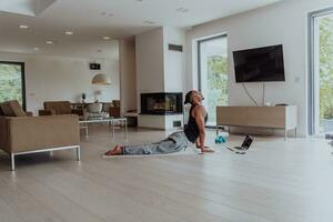 Training At Home. Sporty man doing training while watching online tutorial on laptop, exercising in living room, free space photo