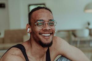 Head shot of African American man wearing glasses and headphones sitting on living room floor photo