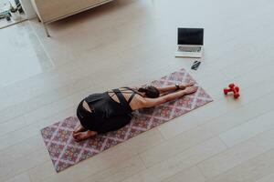 Young Beautiful Female Exercising, Stretching and Practising Yoga with Trainer via Video Call Conference in Bright Sunny House. Healthy Lifestyle, Wellbeing and Mindfulness Concept. photo