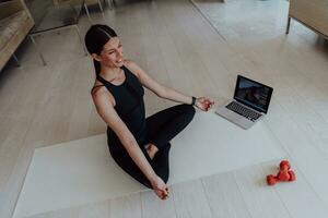 Young Beautiful Female Exercising, Stretching and Practising Yoga with Trainer via Video Call Conference in Bright Sunny House. Healthy Lifestyle, Wellbeing and Mindfulness Concept. photo