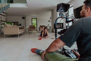 detrás el escena. foto de un camarógrafo grabación un mujer haciendo yoga ejercicios a un en línea formación mientras utilizando y acecho un ordenador portátil