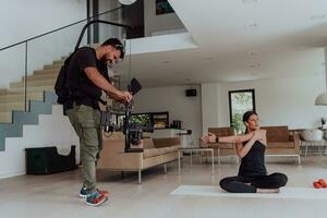 detrás el escena. foto de un camarógrafo grabación un mujer haciendo yoga ejercicios a un en línea formación mientras utilizando y acecho un ordenador portátil