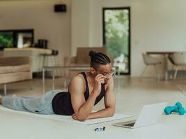 Training At Home. Sporty man doing training while watching online tutorial on laptop, exercising in living room, free space photo