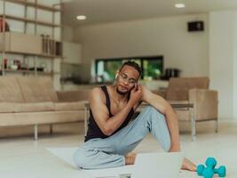 Training At Home. Sporty man doing training while watching online tutorial on laptop, exercising in living room, free space photo