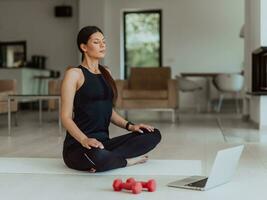 Young Beautiful Female Exercising, Stretching and Practising Yoga with Trainer via Video Call Conference in Bright Sunny House. Healthy Lifestyle, Wellbeing and Mindfulness Concept. photo