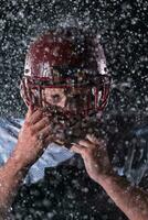 American Football Field Lonely Athlete Warrior Standing on a Field Holds his Helmet and Ready to Play. Player Preparing to Run, Attack and Score Touchdown. Rainy Night with Dramatic Fog, Blue Light photo