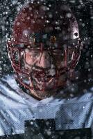 American Football Field Lonely Athlete Warrior Standing on a Field Holds his Helmet and Ready to Play. Player Preparing to Run, Attack and Score Touchdown. Rainy Night with Dramatic Fog, Blue Light photo