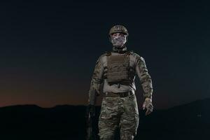 Army soldier in Combat Uniforms with an assault rifle, plate carrier and combat helmet going on a dangerous mission on a rainy night. photo
