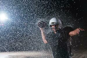 American Football Field Lonely Athlete Warrior Standing on a Field Holds his Helmet and Ready to Play. Player Preparing to Run, Attack and Score Touchdown. Rainy Night with Dramatic Fog, Blue Light photo