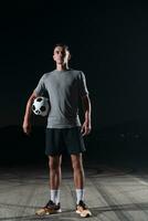 portrait of a young handsome soccer player man on a street playing with a football ball. photo