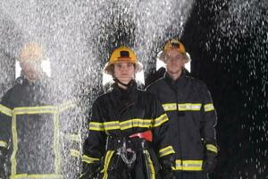 retrato de un grupo de bomberos en pie y caminando valiente y optimista con un hembra como equipo líder. foto