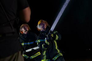 bomberos utilizar un agua manguera a eliminar un fuego peligro. equipo de bomberos en el peligroso rescate misión. foto