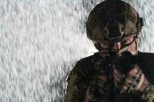 Ejército soldado en combate uniformes con un asalto rifle, plato portador y combate casco yendo en un peligroso misión en un lluvioso noche. foto